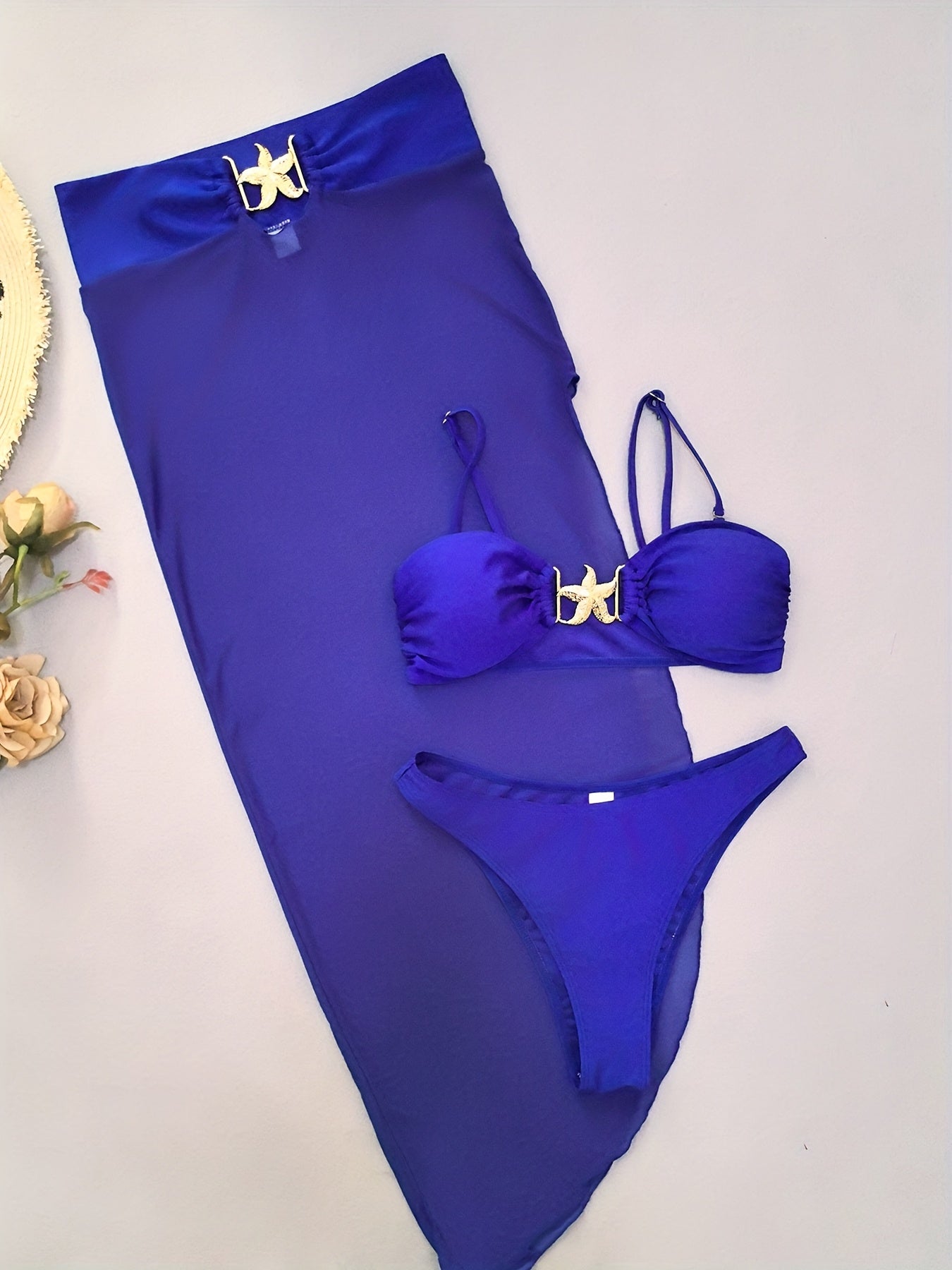 Biquíni feminino azul 3 peças com saia de tule e estrela dourada em flat lay
