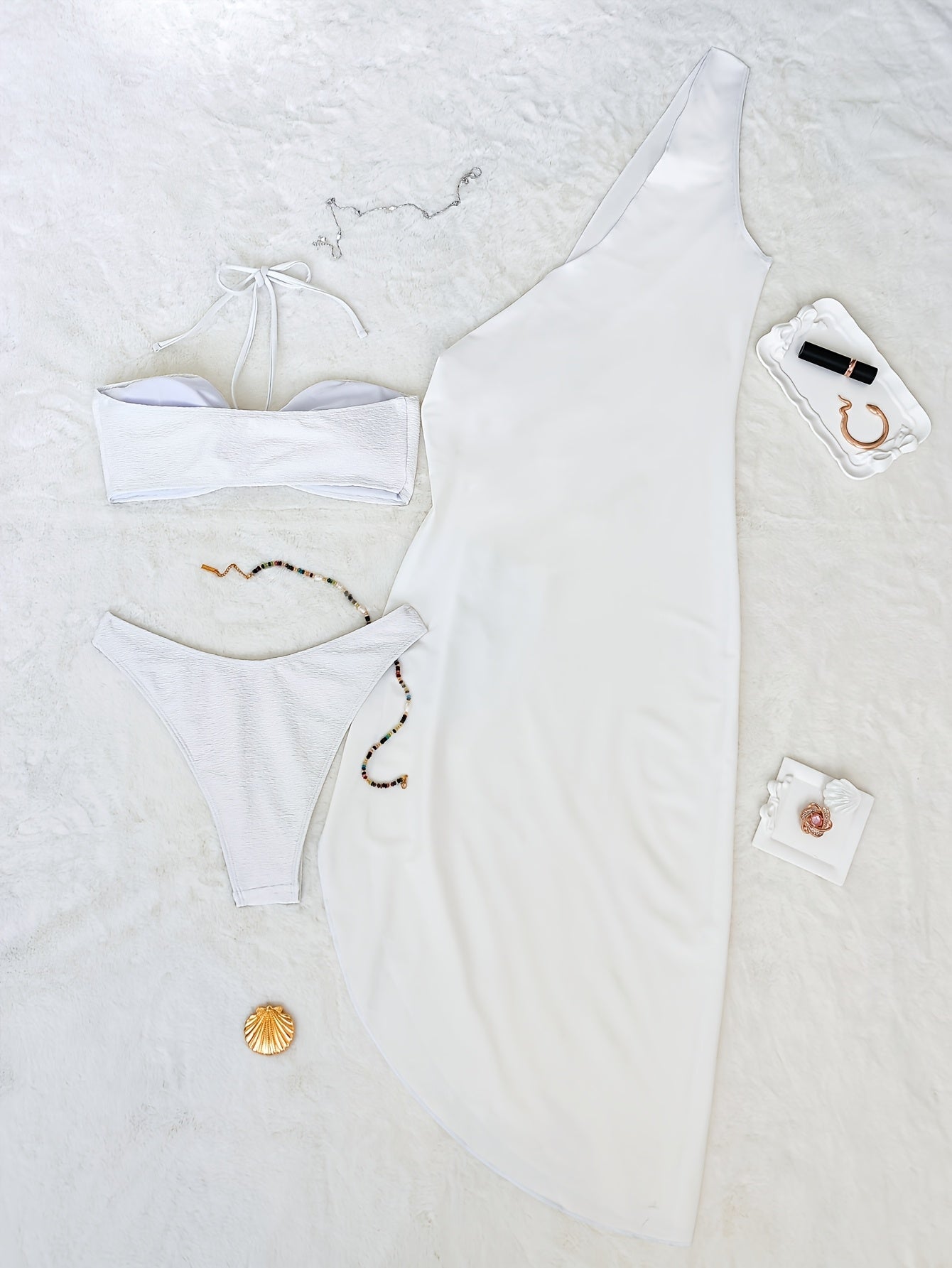 Conjunto biquíni branco elegante com saia pareô disposto sobre superfície que lembra uma cama