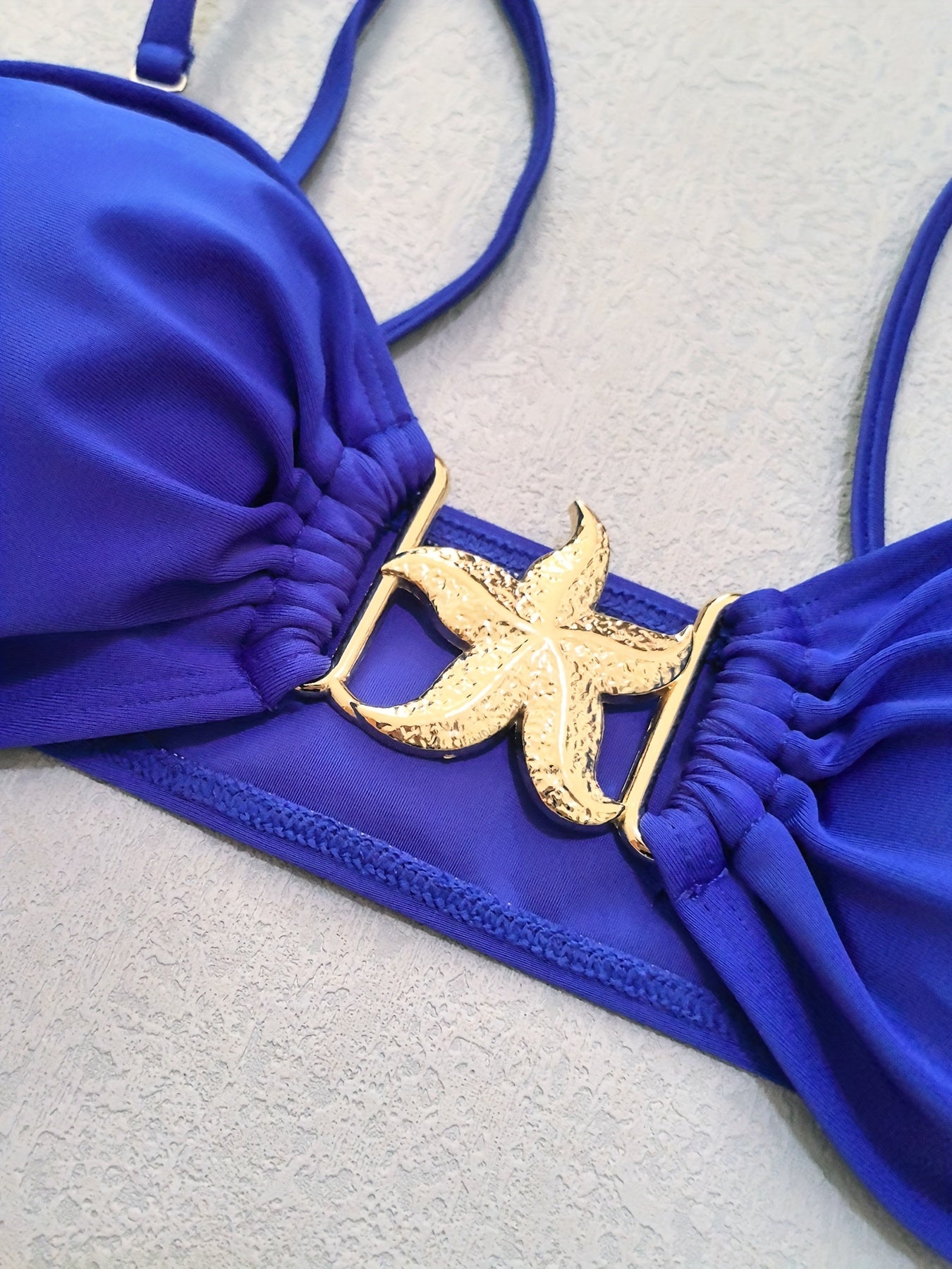 Detalhe do top azul do biquíni feminino com estrela dourada sexy
