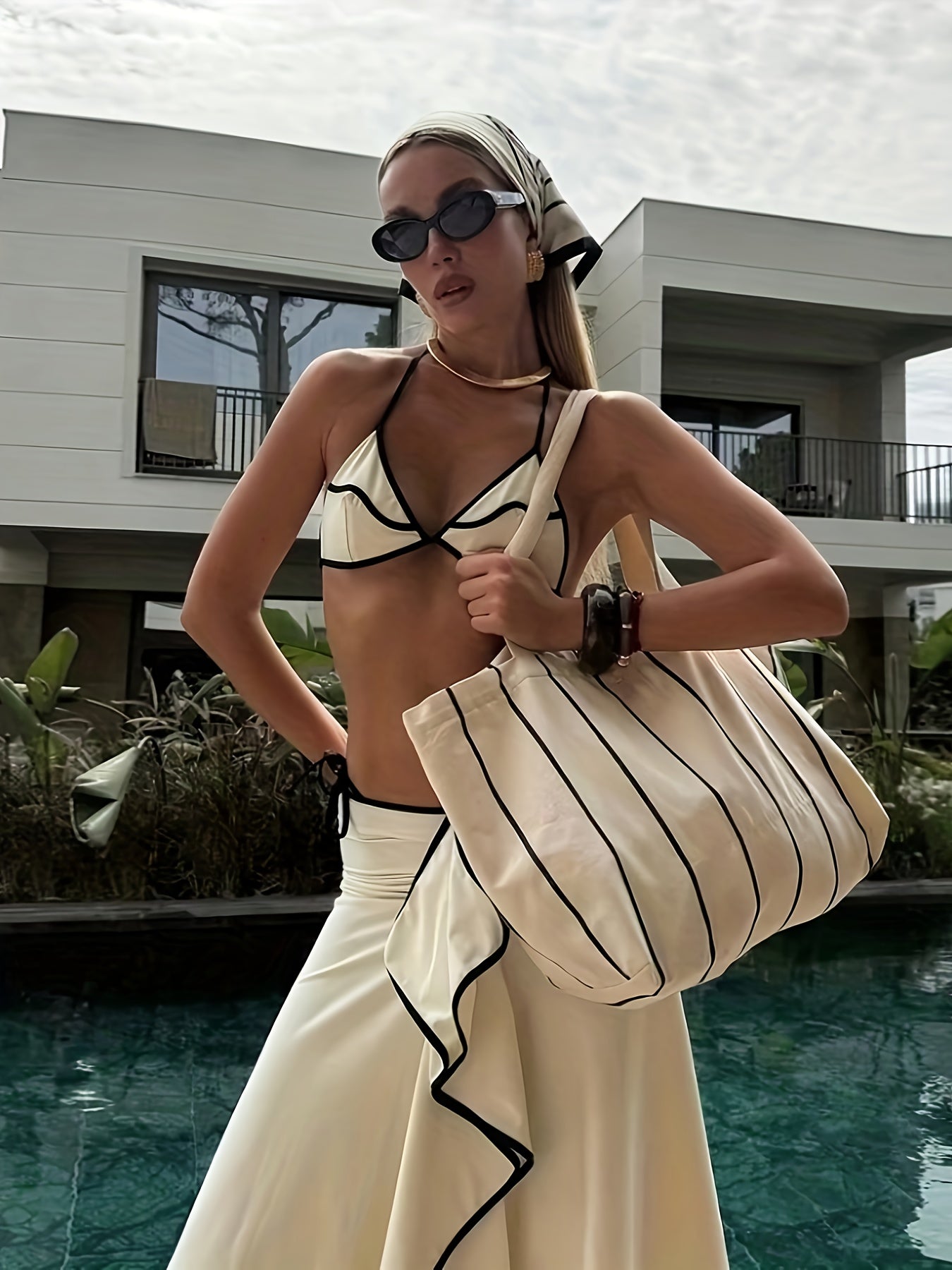 Look praia feminino com saída de praia bege, biquíni preto e bolsa de palha